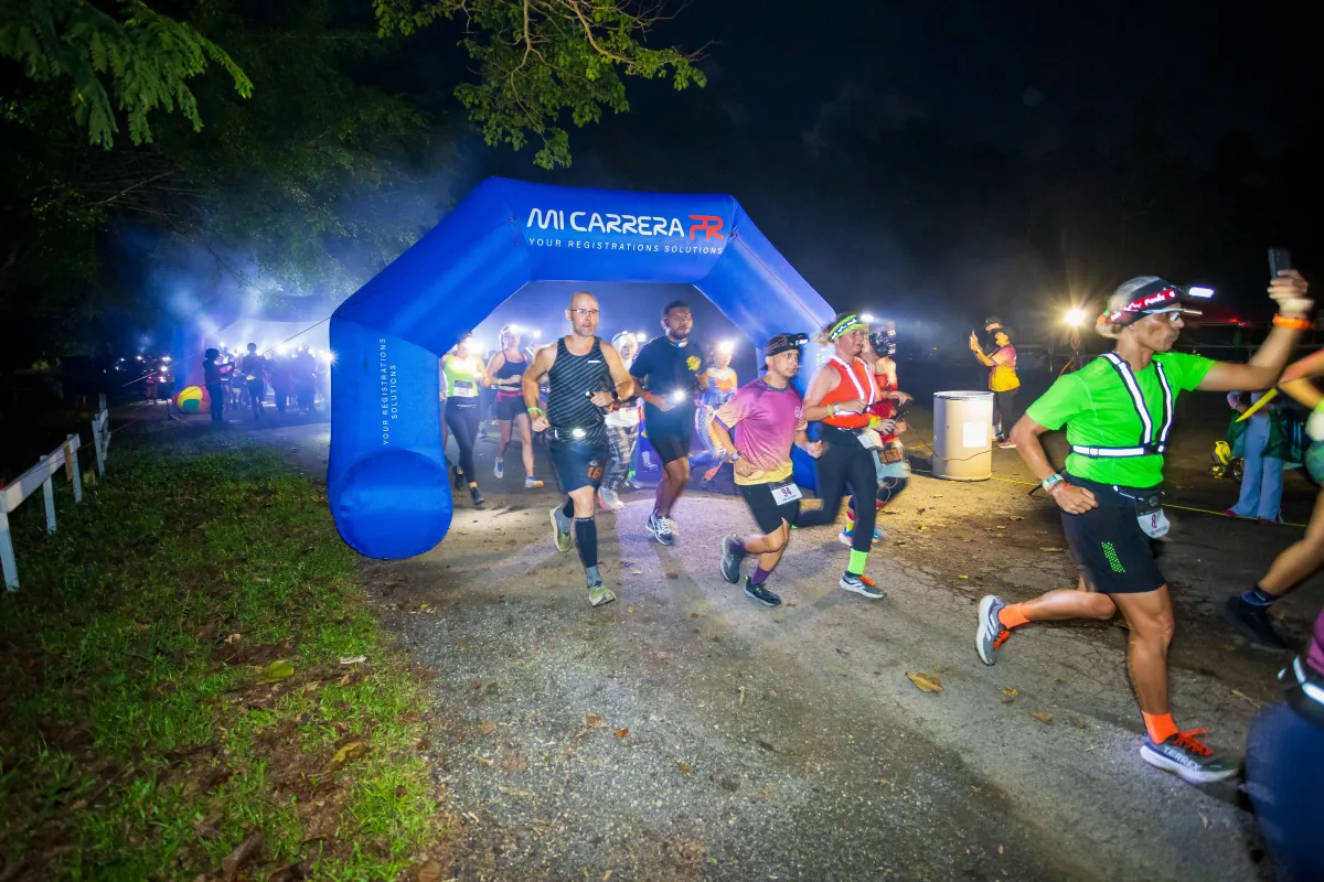 Atletas iniciando un evento nocturno bajo el arco de MiCarreraPR
